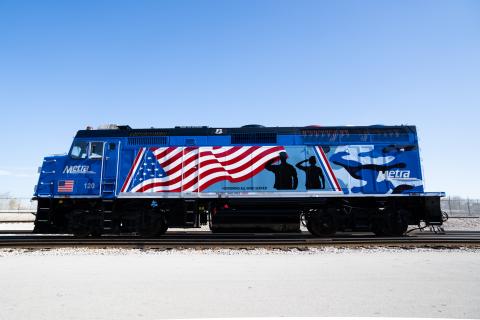 Metra locomotive with flag and military members saluting to honor all veterans